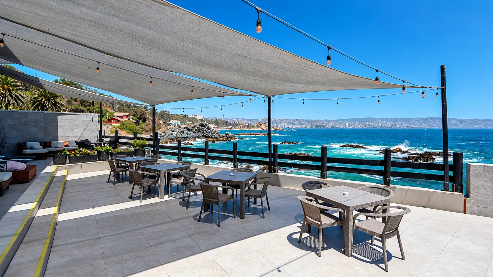Terraza del restaurante con mesas bajo toldos y vista al océano Pacífico